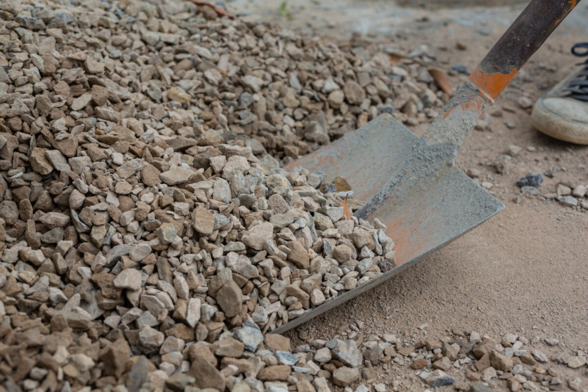 Man digging into recycled aggregate pile, illustrating sustainable construction.