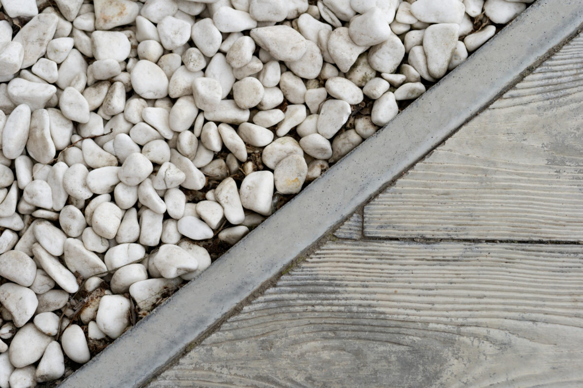 Photo of white decorative pebbles meeting a wooden deck, illustrating elegant landscaping design and outdoor decor.