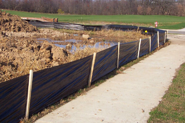 Photo of silt fencing preventing dirt from falling onto a footpath, showcasing erosion control measures.