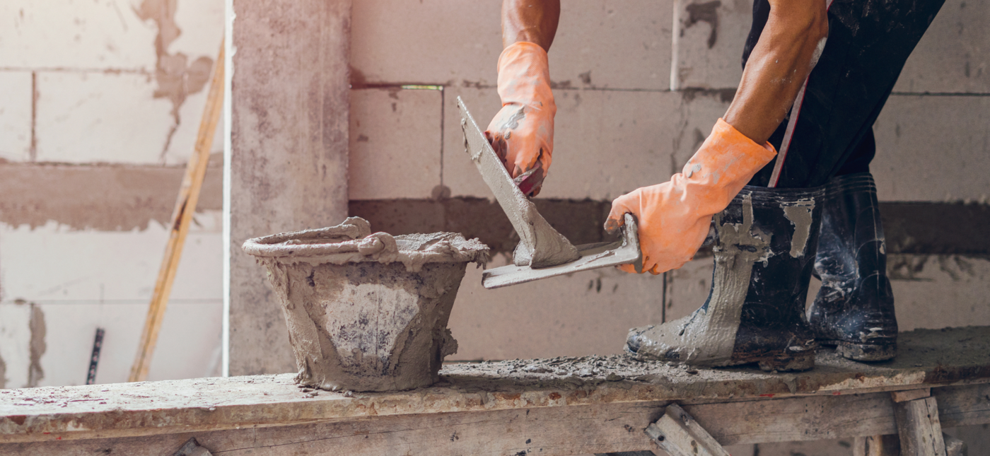 Photo of a tradesman applying cement mix onto his trowel, illustrating construction or masonry work.