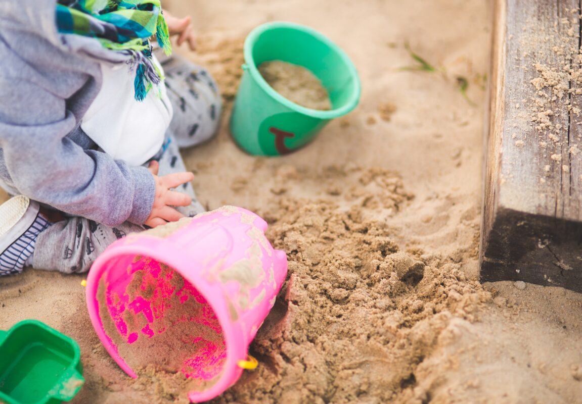 Photo of a child playing in a sandpit, illustrating outdoor play and fun.