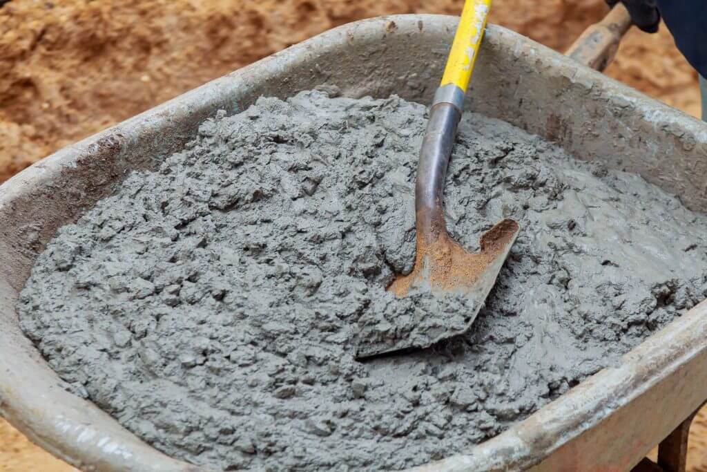 Photo of cement mixing in a wheelbarrow with a shovel, illustrating construction or DIY activities.