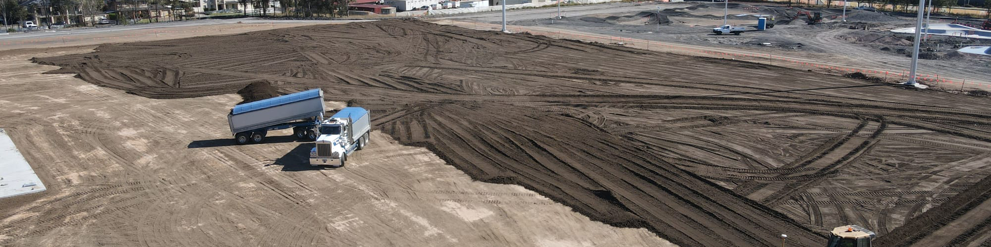 Drone shot of a truck unloading soil onto a lot, illustrating construction or landscaping activities from above.